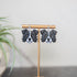 Border collie Dog-shaped earrings on a stand with a plant in the background