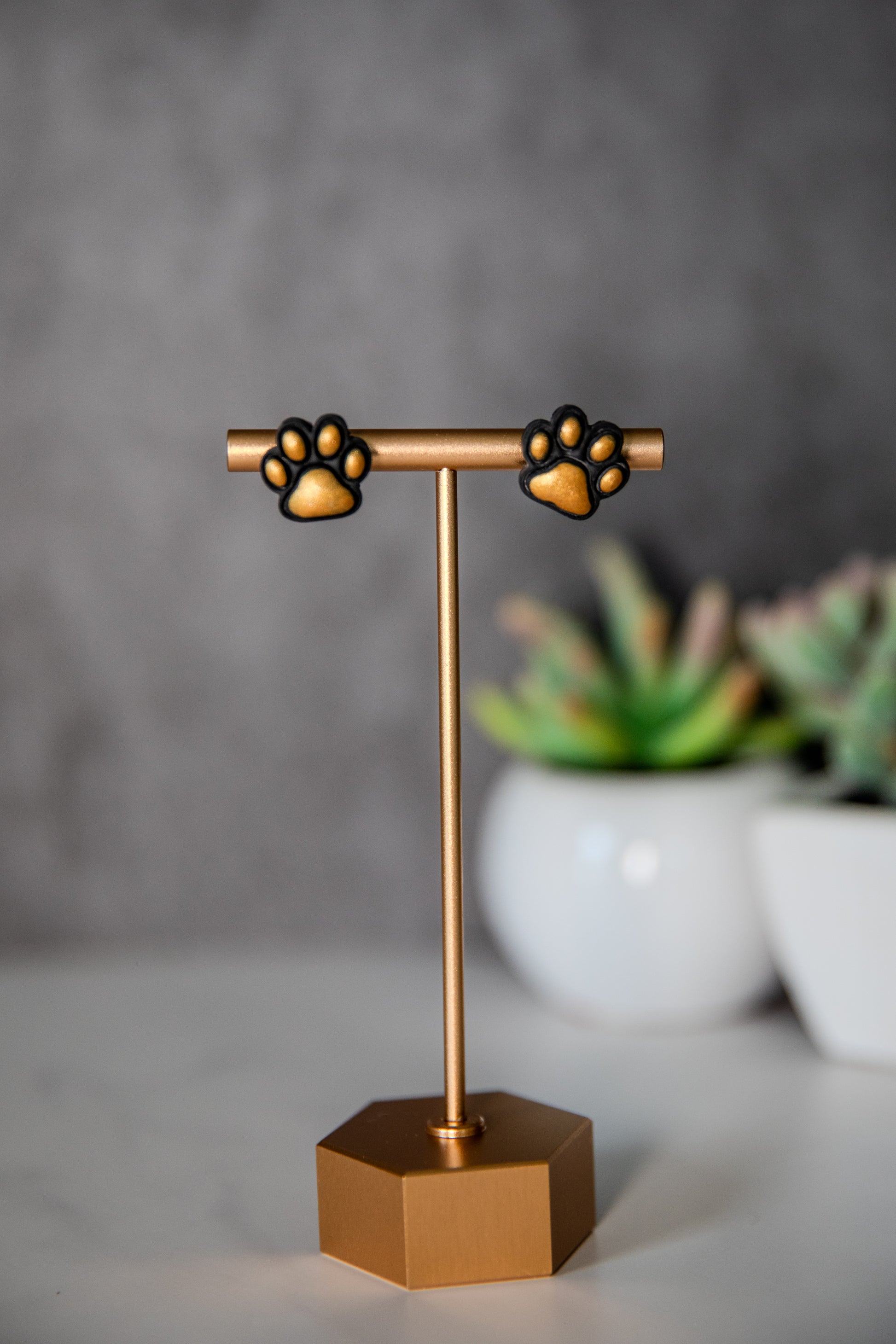 Black paw print stud earrings with gold pads