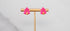 Pink tree-shaped earrings on a gold earring stand against a light gray background