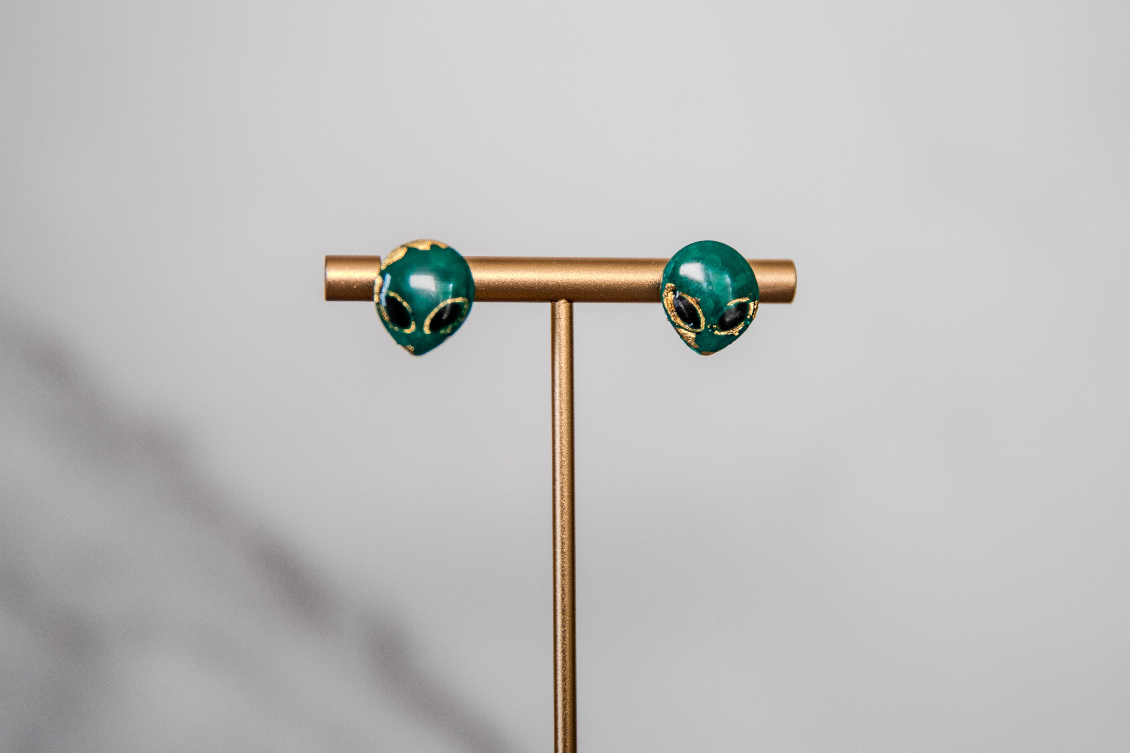 Small green alien face stud earrings with gold detailing