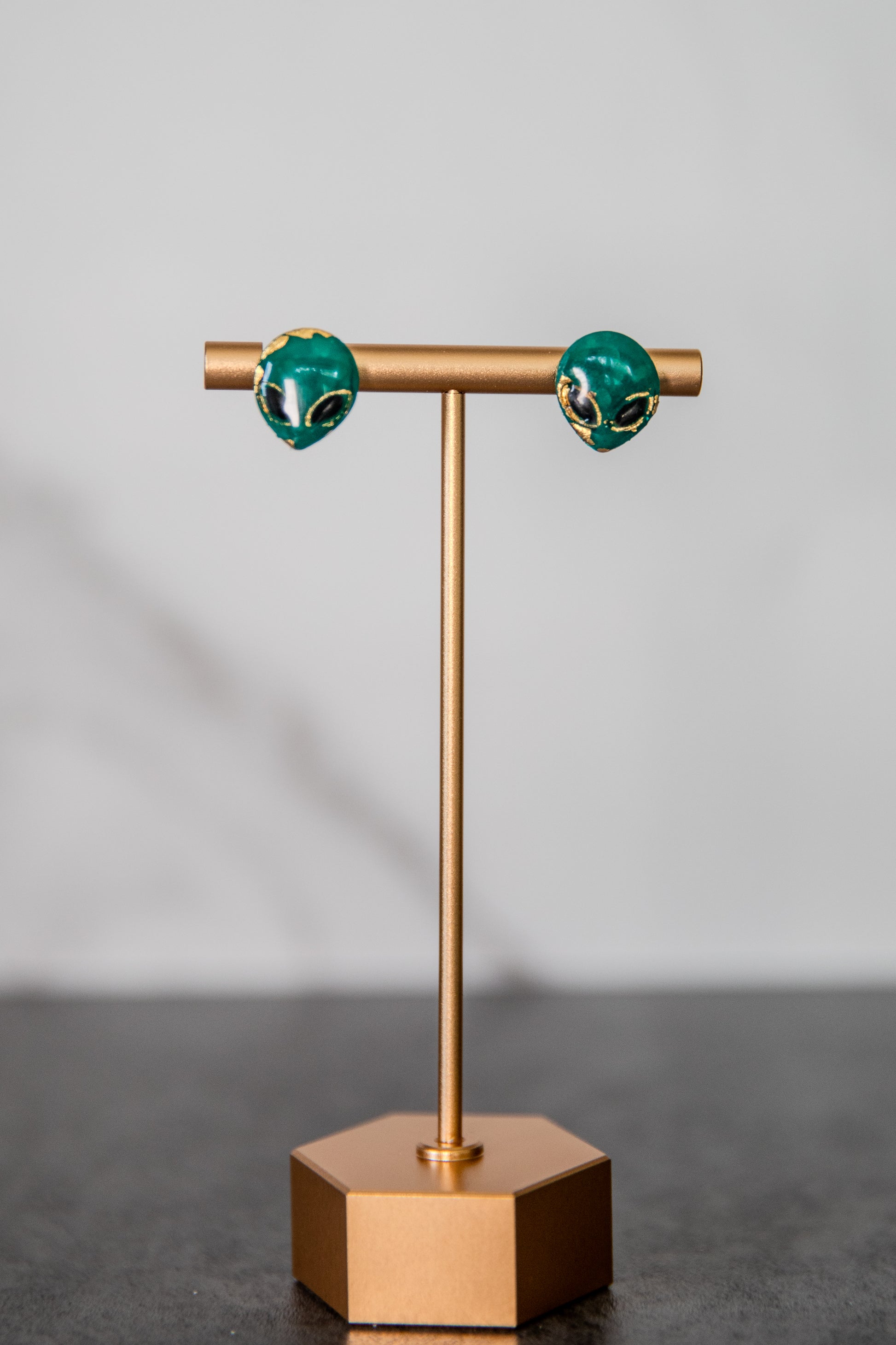 Small green alien face stud earrings with gold detailing