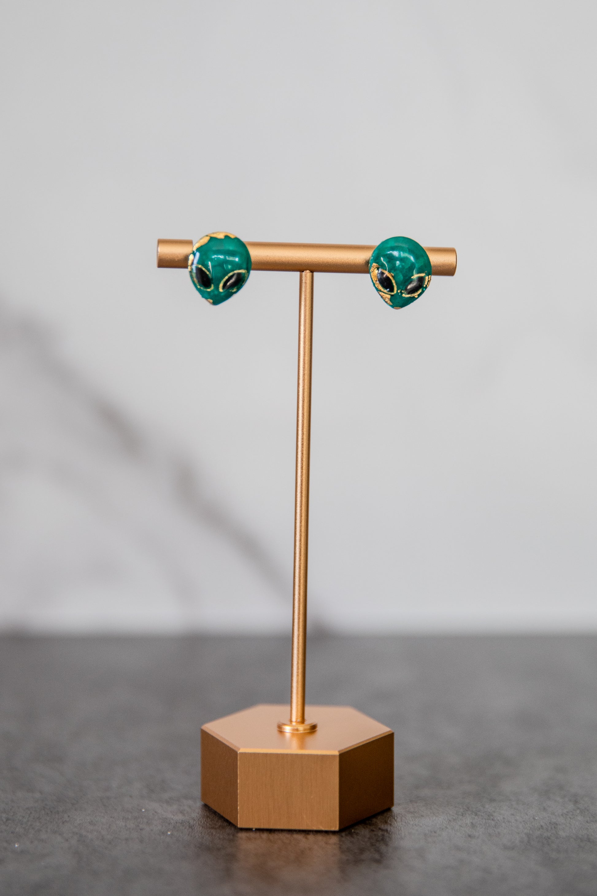 Small green alien face stud earrings with gold detailing