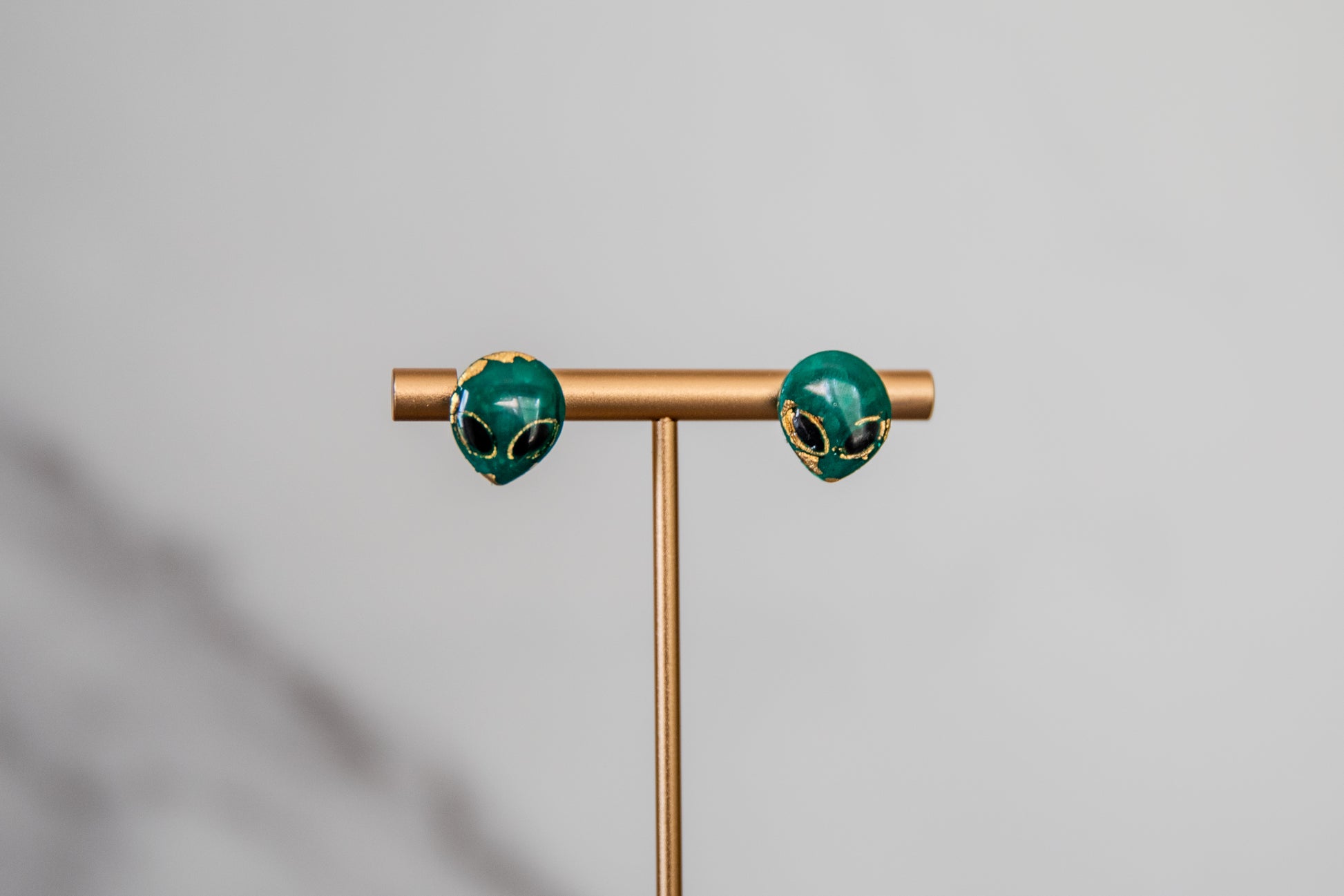 Small green alien face stud earrings with gold detailing