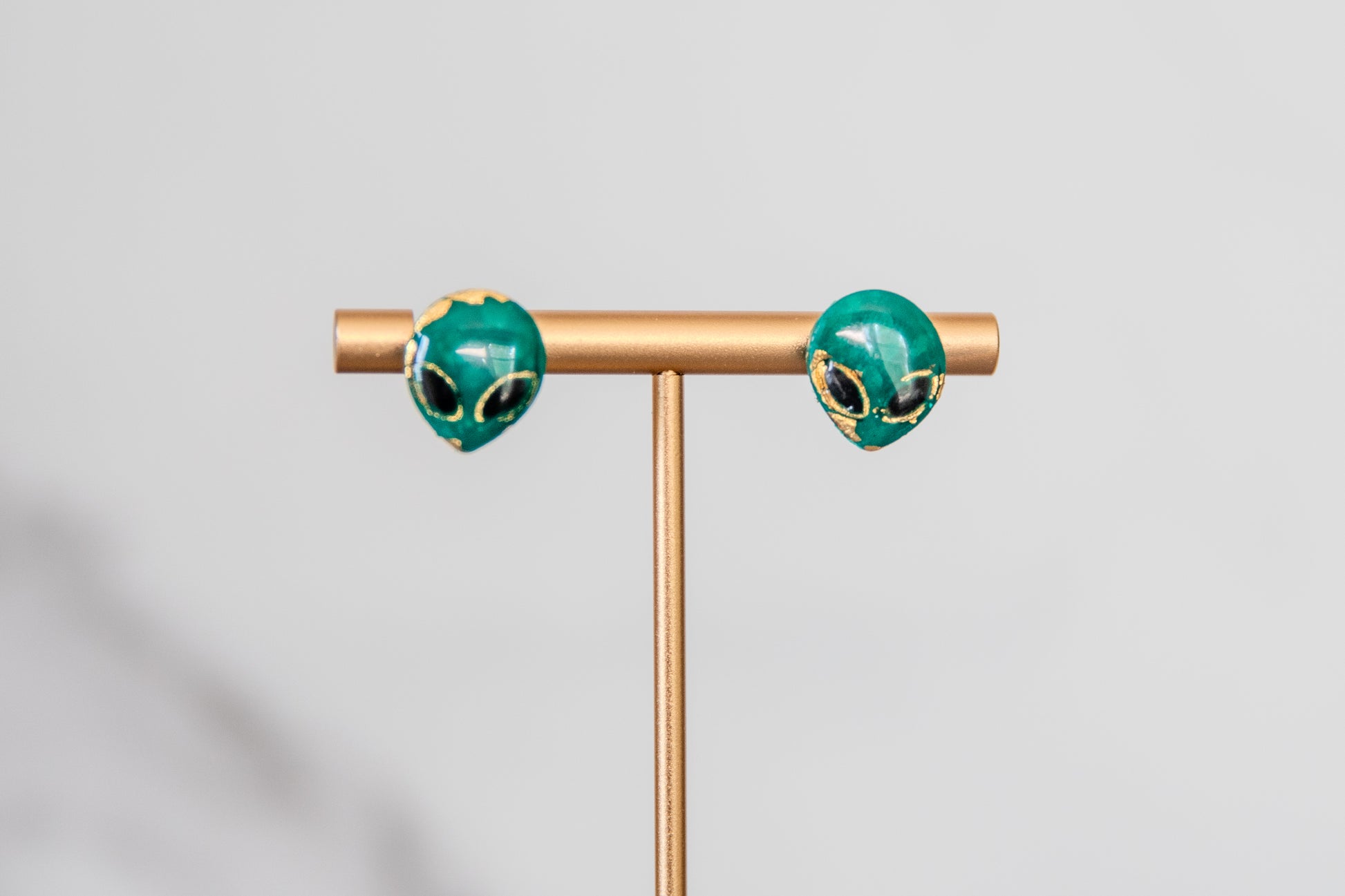 Small green alien face stud earrings with gold detailing