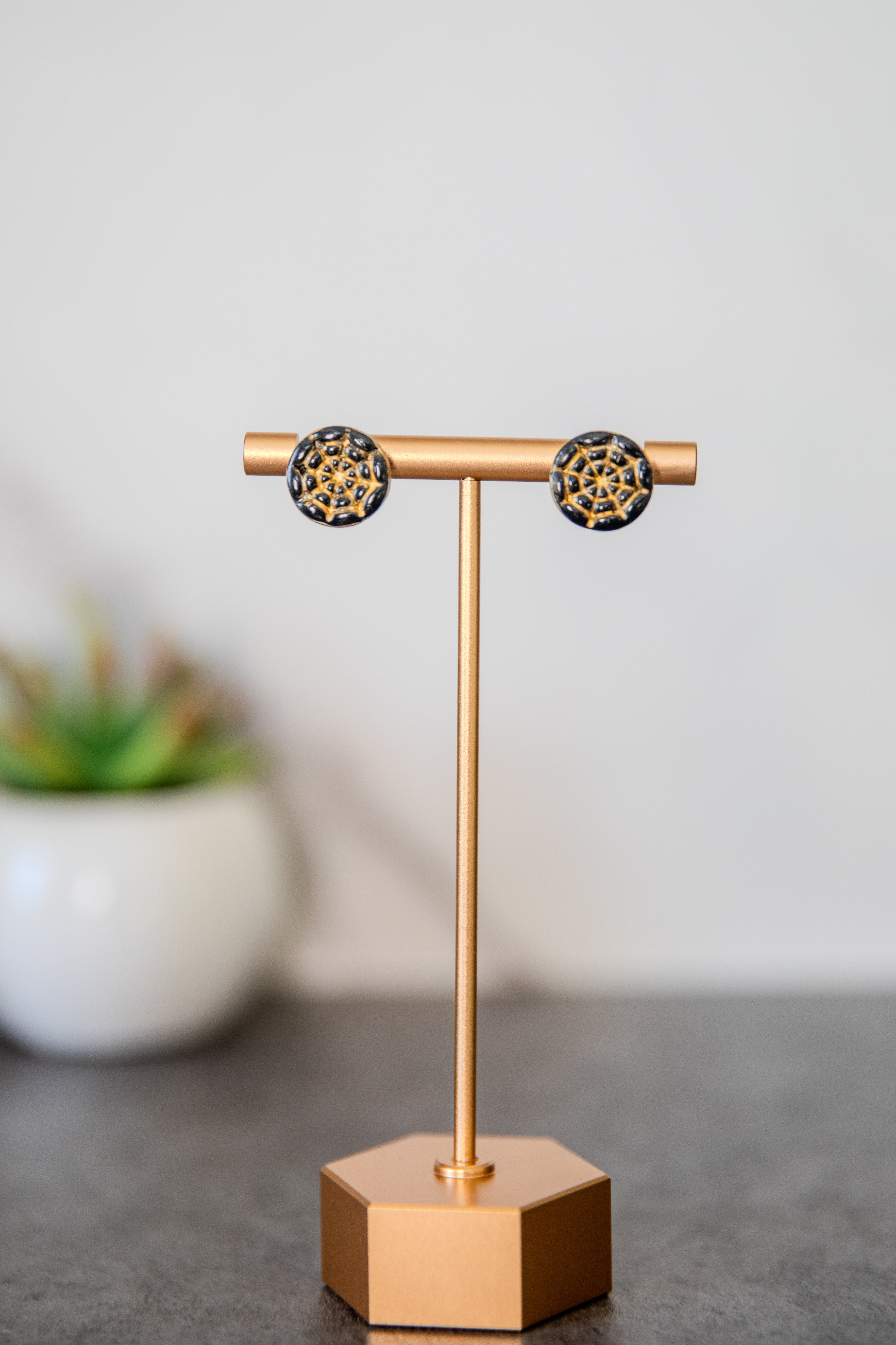 Round black stud earrings with gold spiderweb