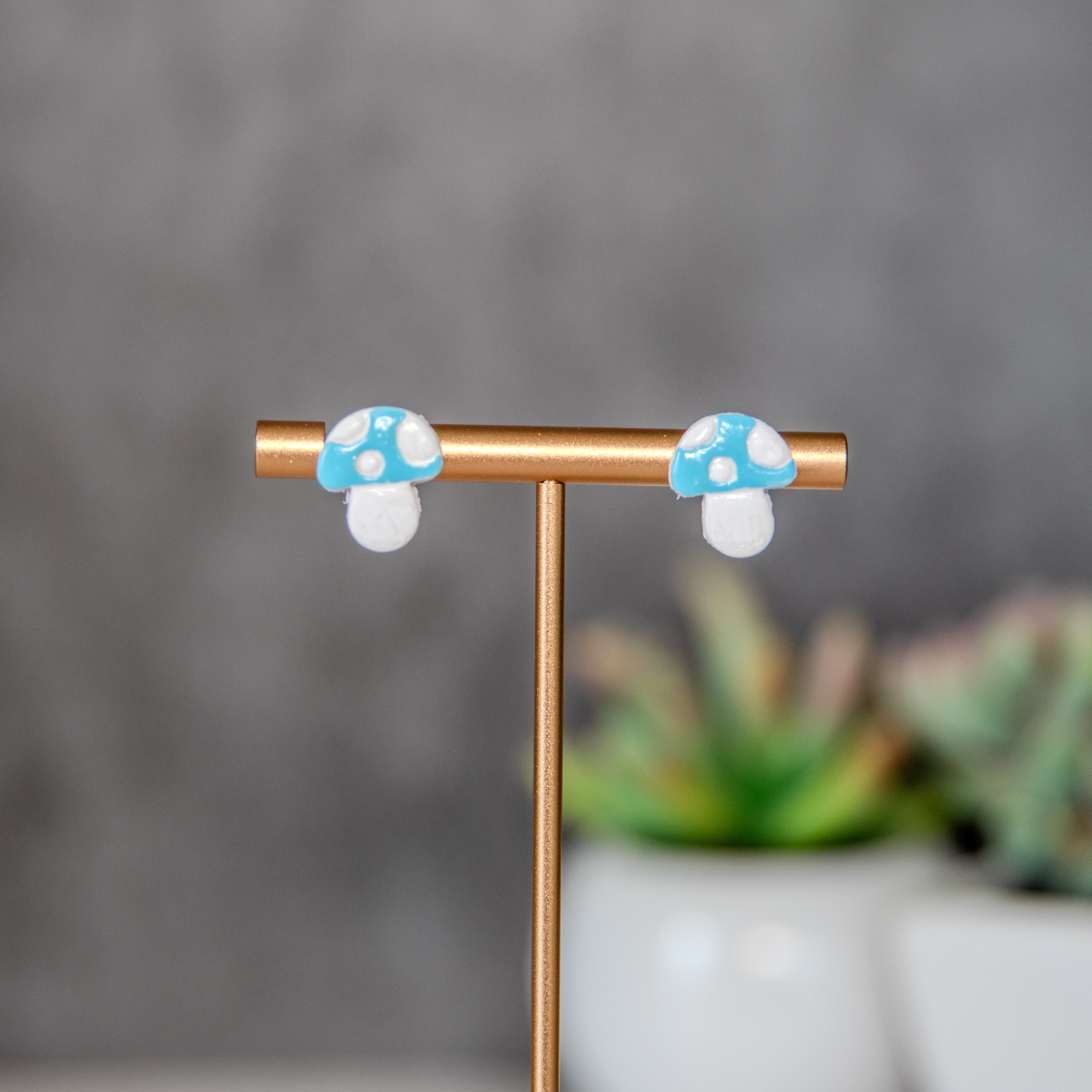 Pair of mushroom-shaped earrings on a stand with a blurred background