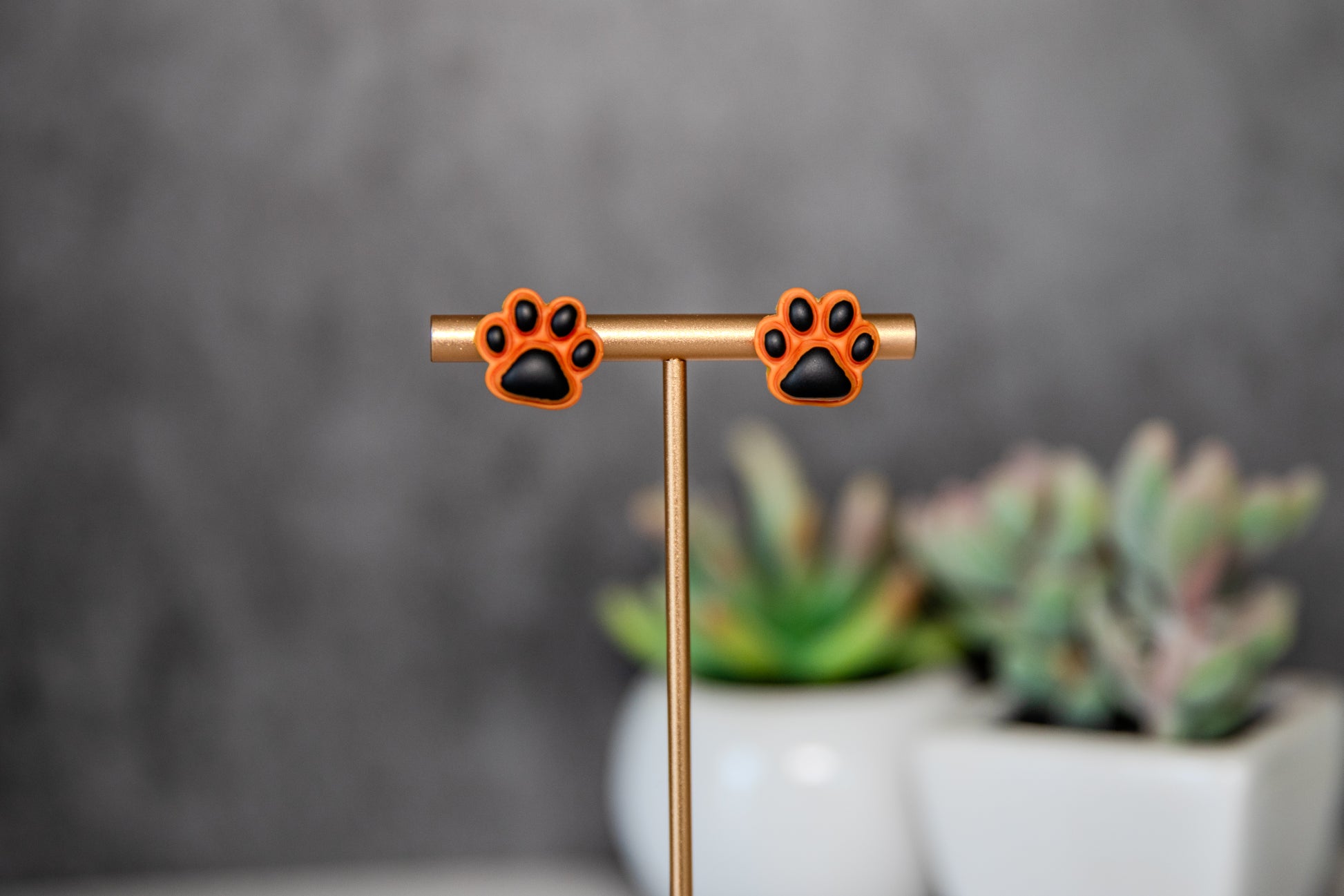 Orange paw print stud earrings with black pads