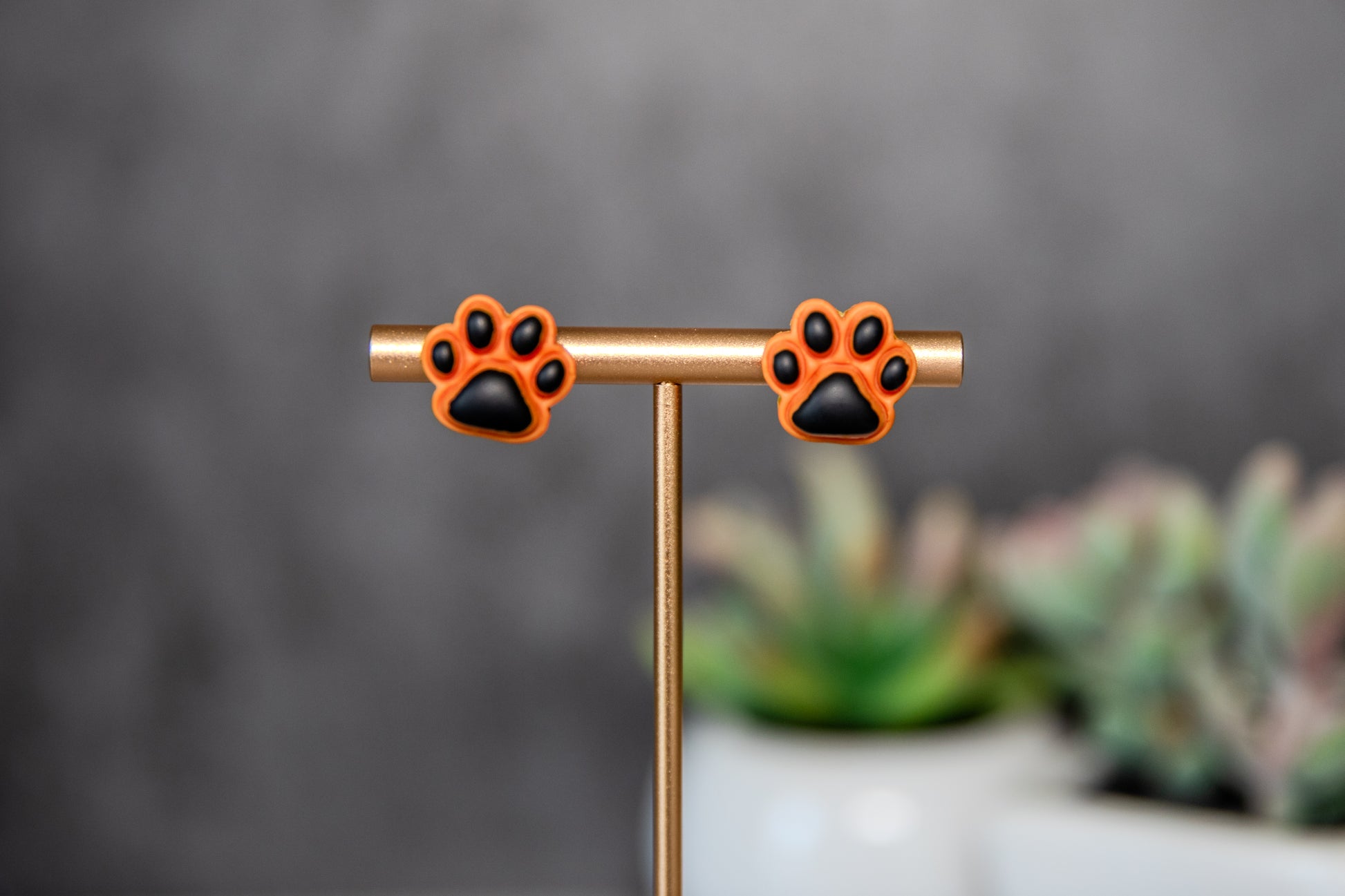 Orange paw print stud earrings with black pads