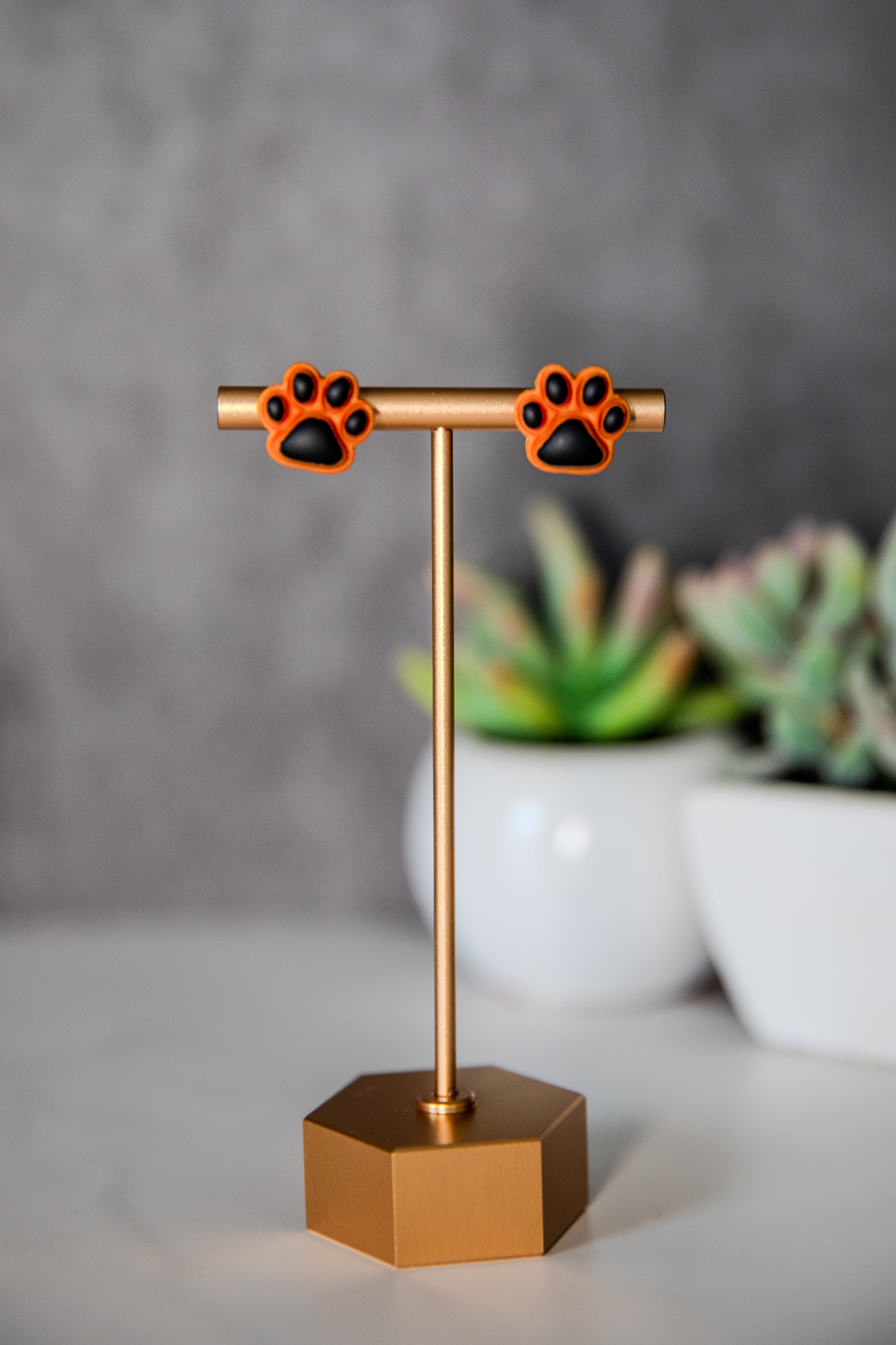 Orange paw print stud earrings with black pads
