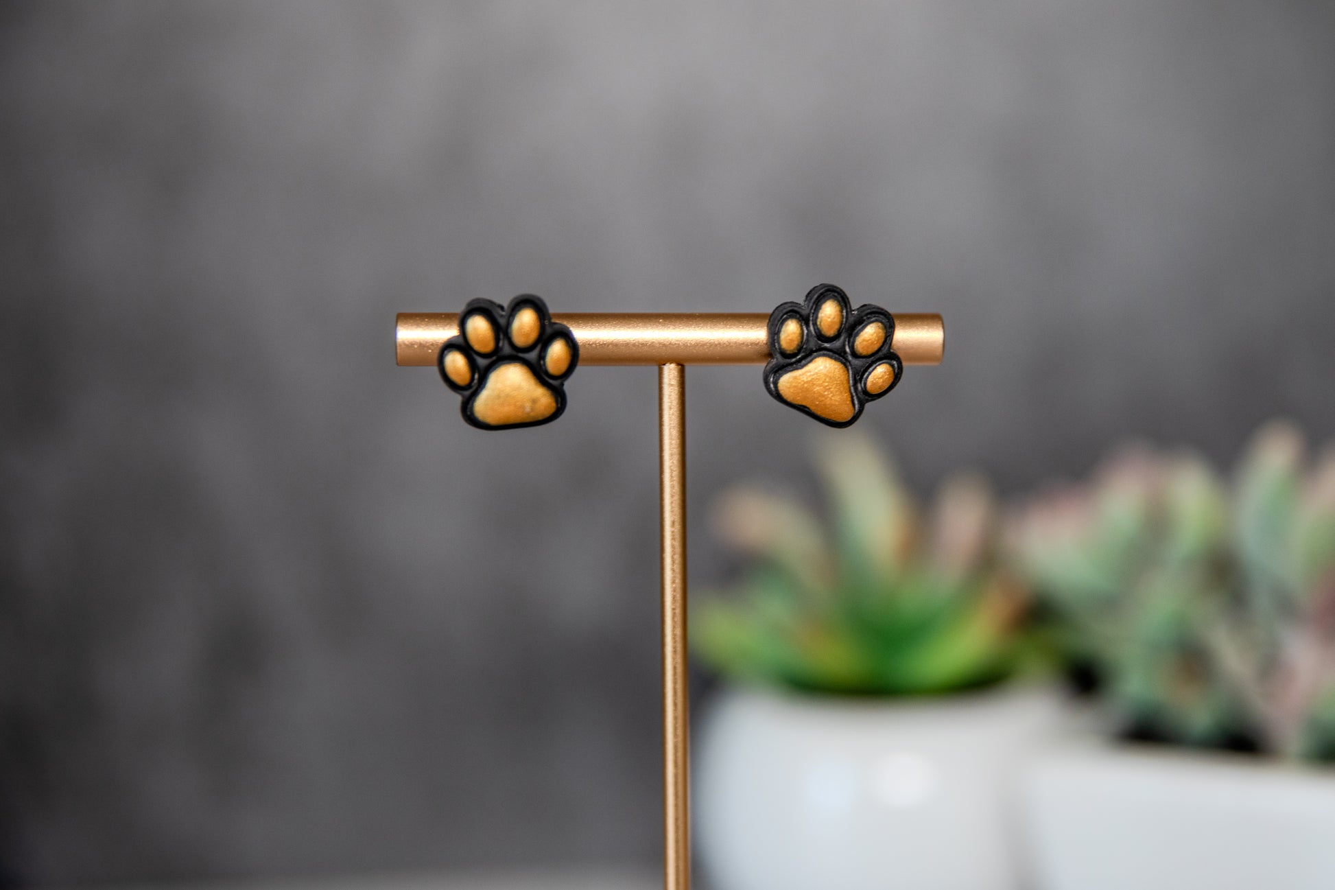 Black paw print stud earrings with gold pads
