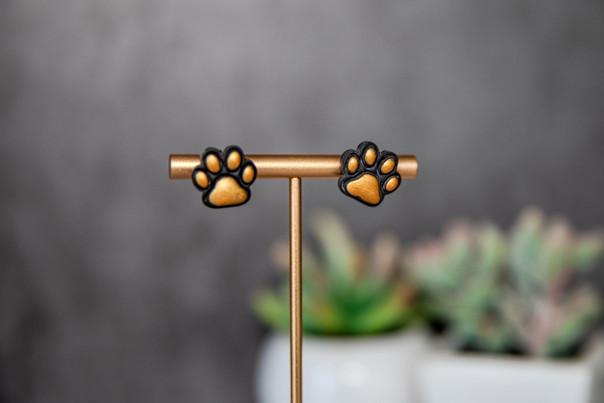 Black paw print stud earrings with gold pads