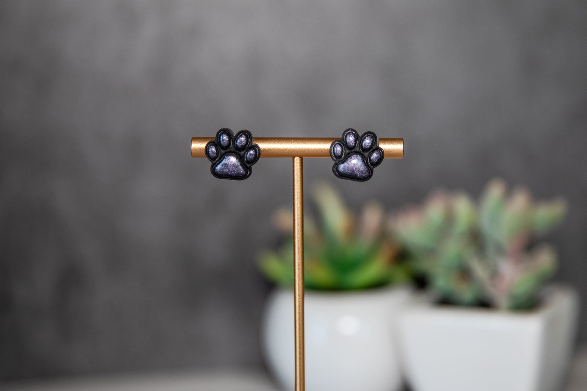 Black paw print stud earrings with shimmer pads
