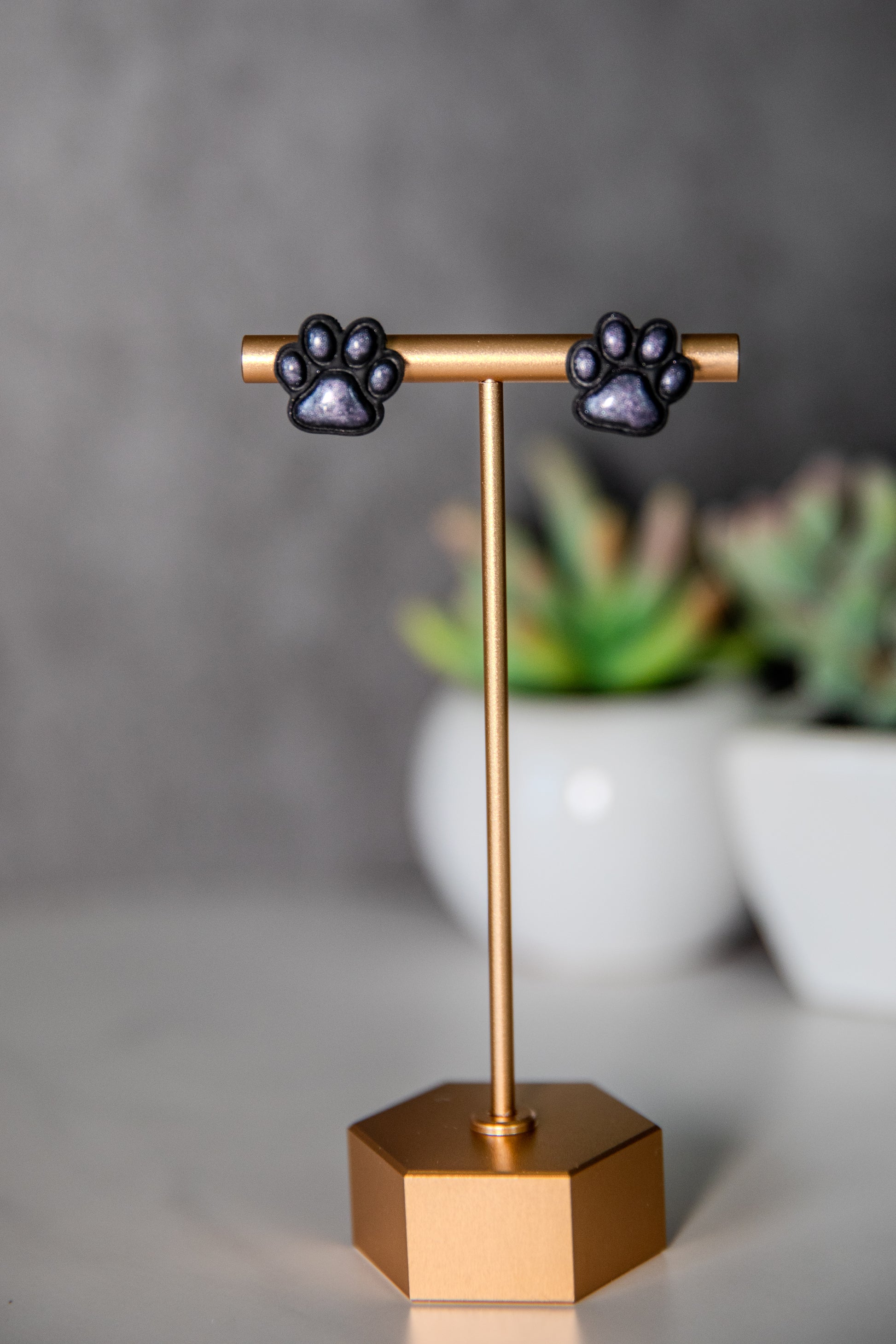 Black paw print stud earrings with shimmer pads