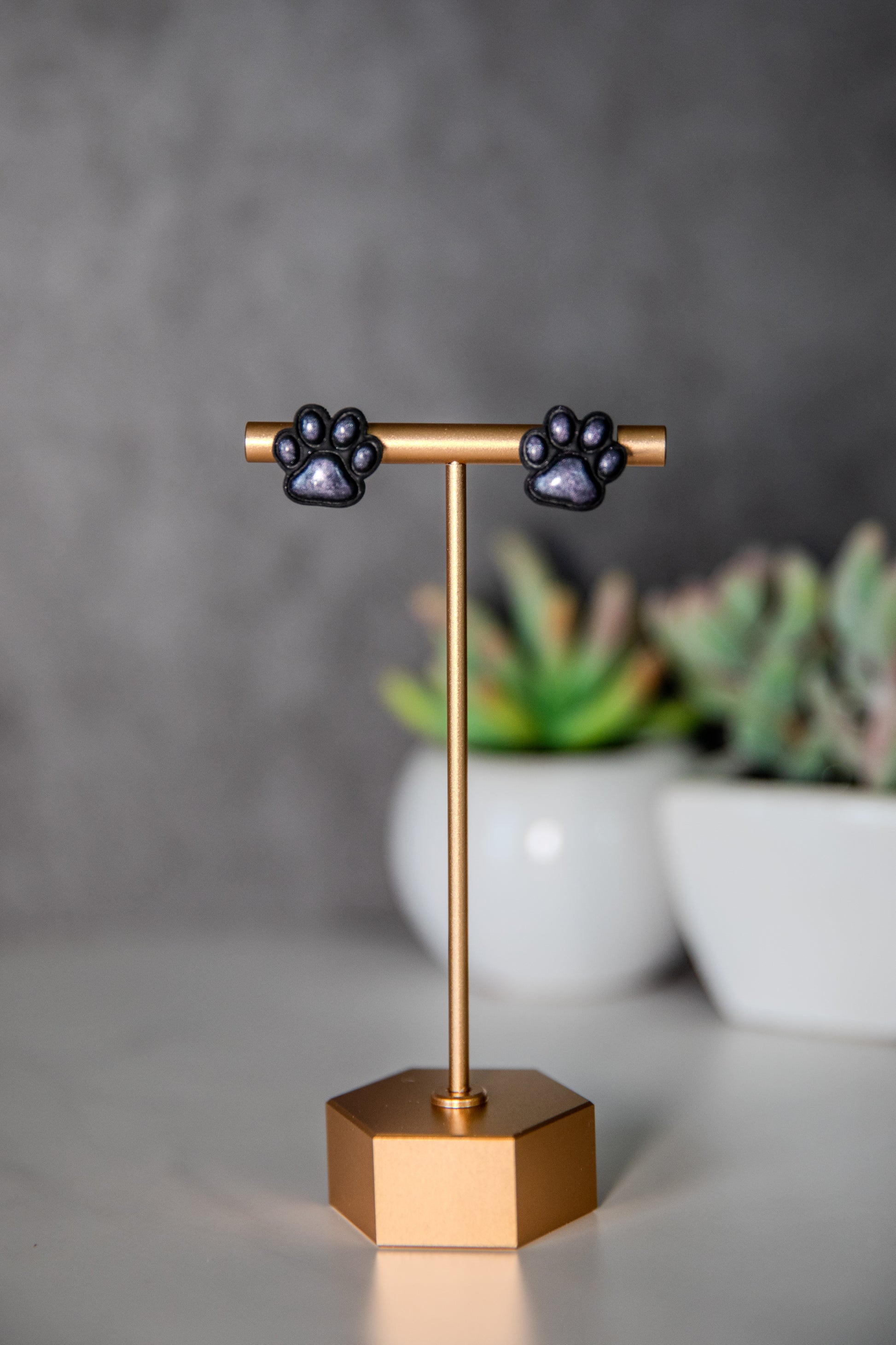 Black paw print stud earrings with shimmer pads