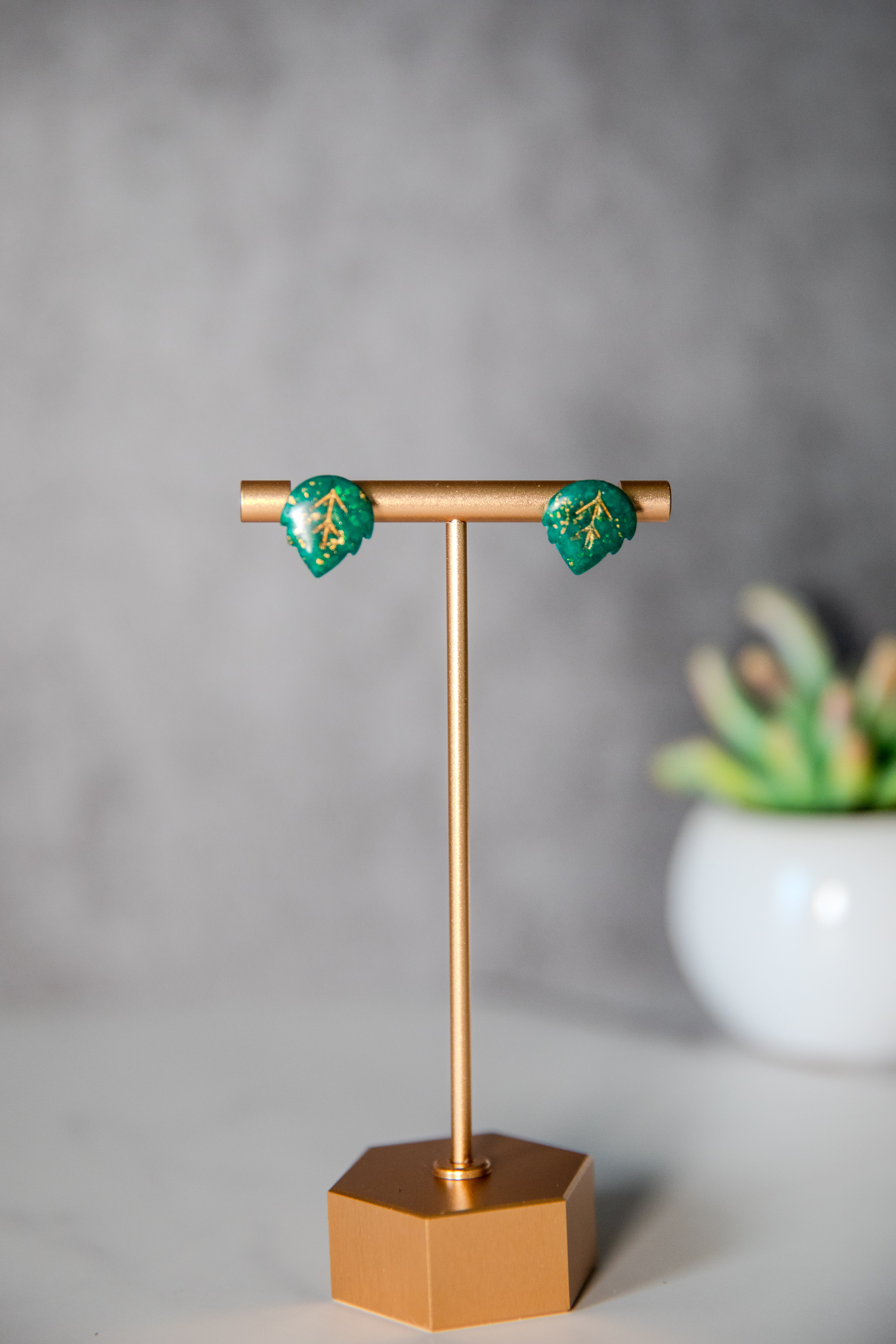 Small green leaf stud earrings with gold detailing
