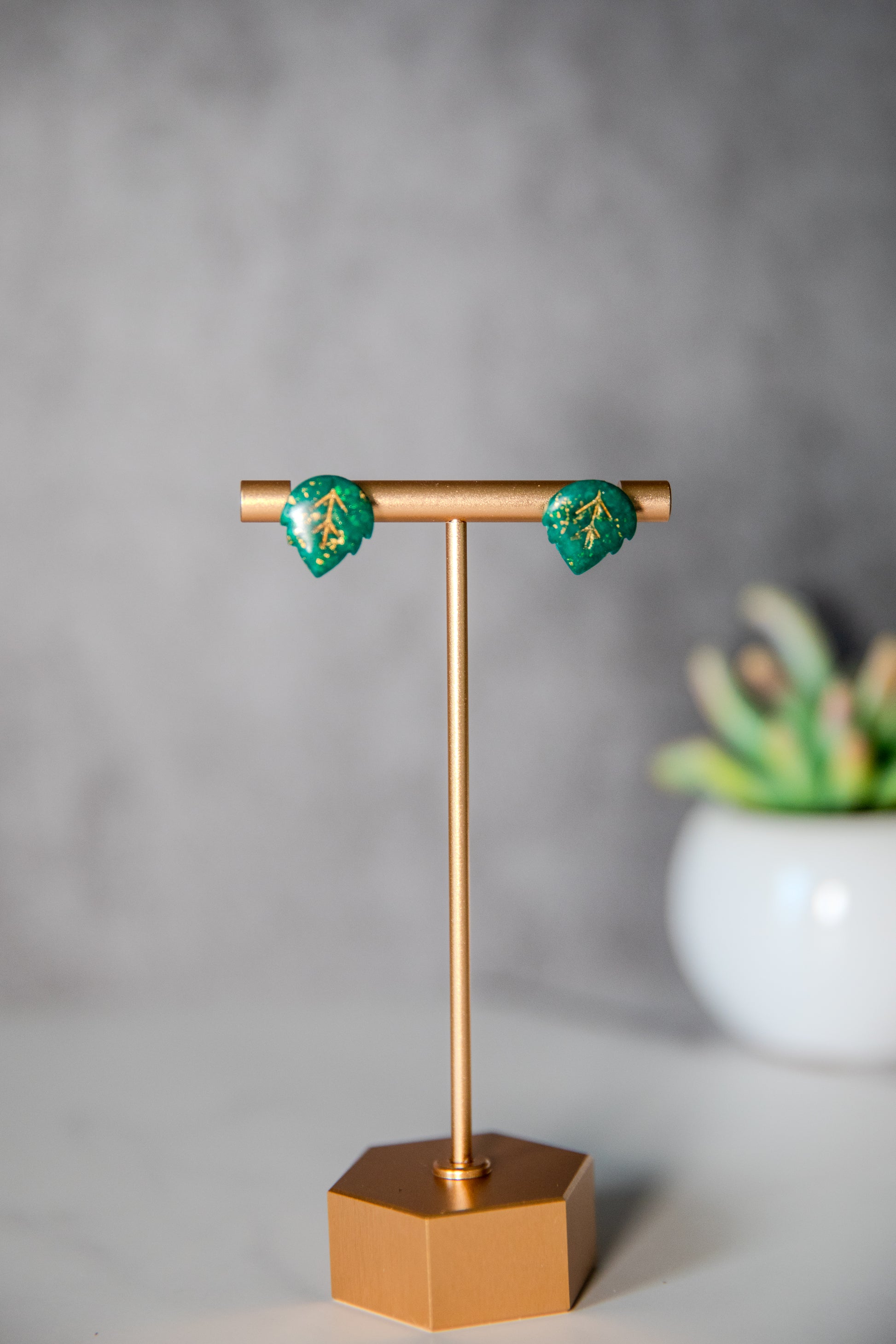 Small green leaf stud earrings with gold detailing