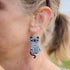Person wearing a cat-shaped earring with a mummy design.