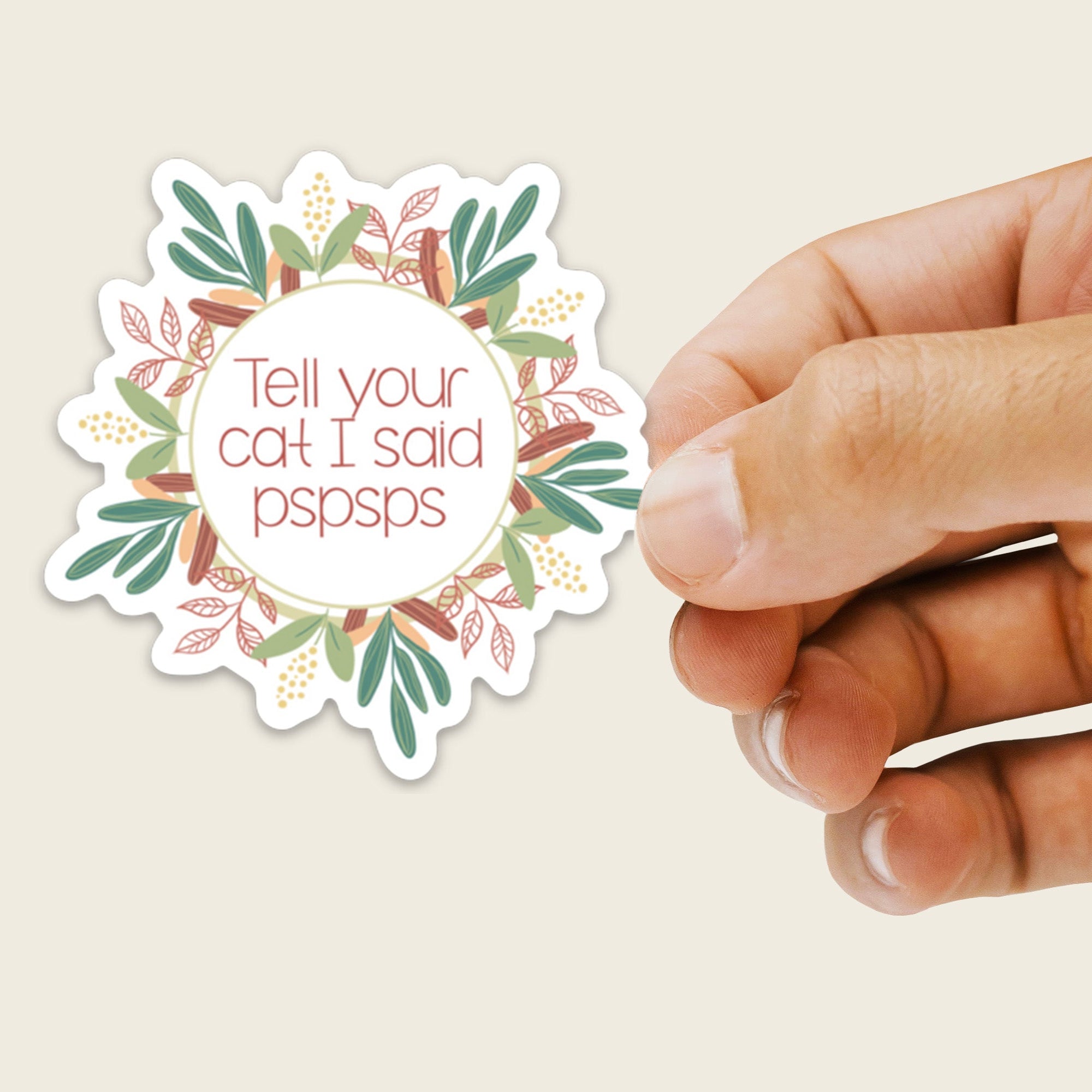 Hand holding a sticker with text and floral design on a beige background