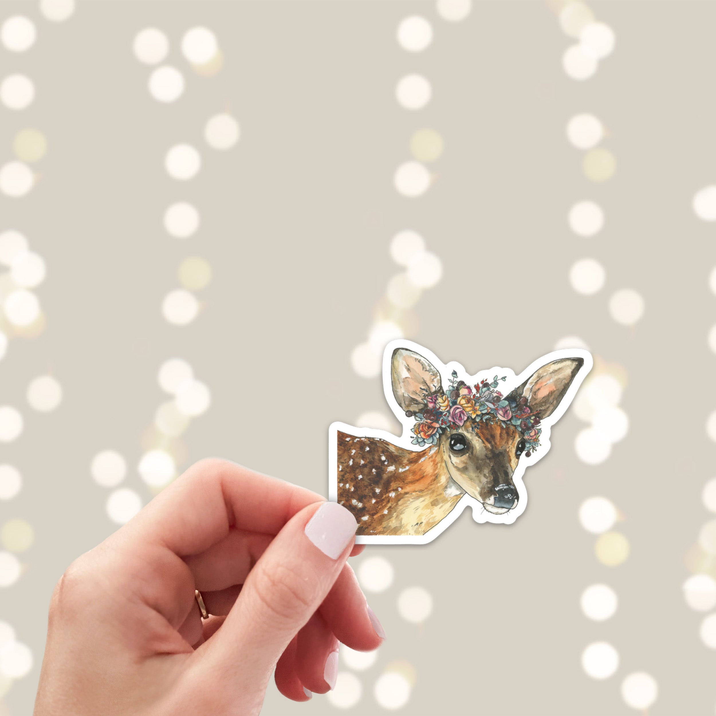 Hand holding a sticker of a deer with a floral crown
