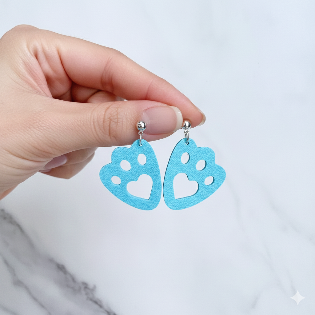Hand holding blue heart-shaped earrings against a light background