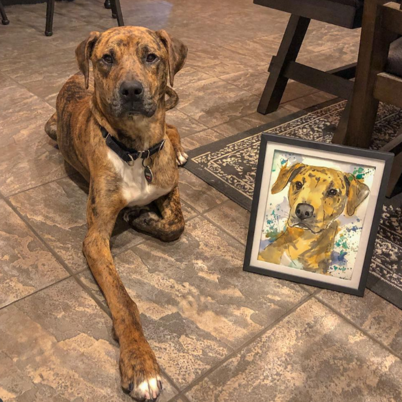 Dog lying on a tiled floor with a framed picture of itself