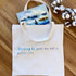 Tote bag with printed text and a card on a wooden surface