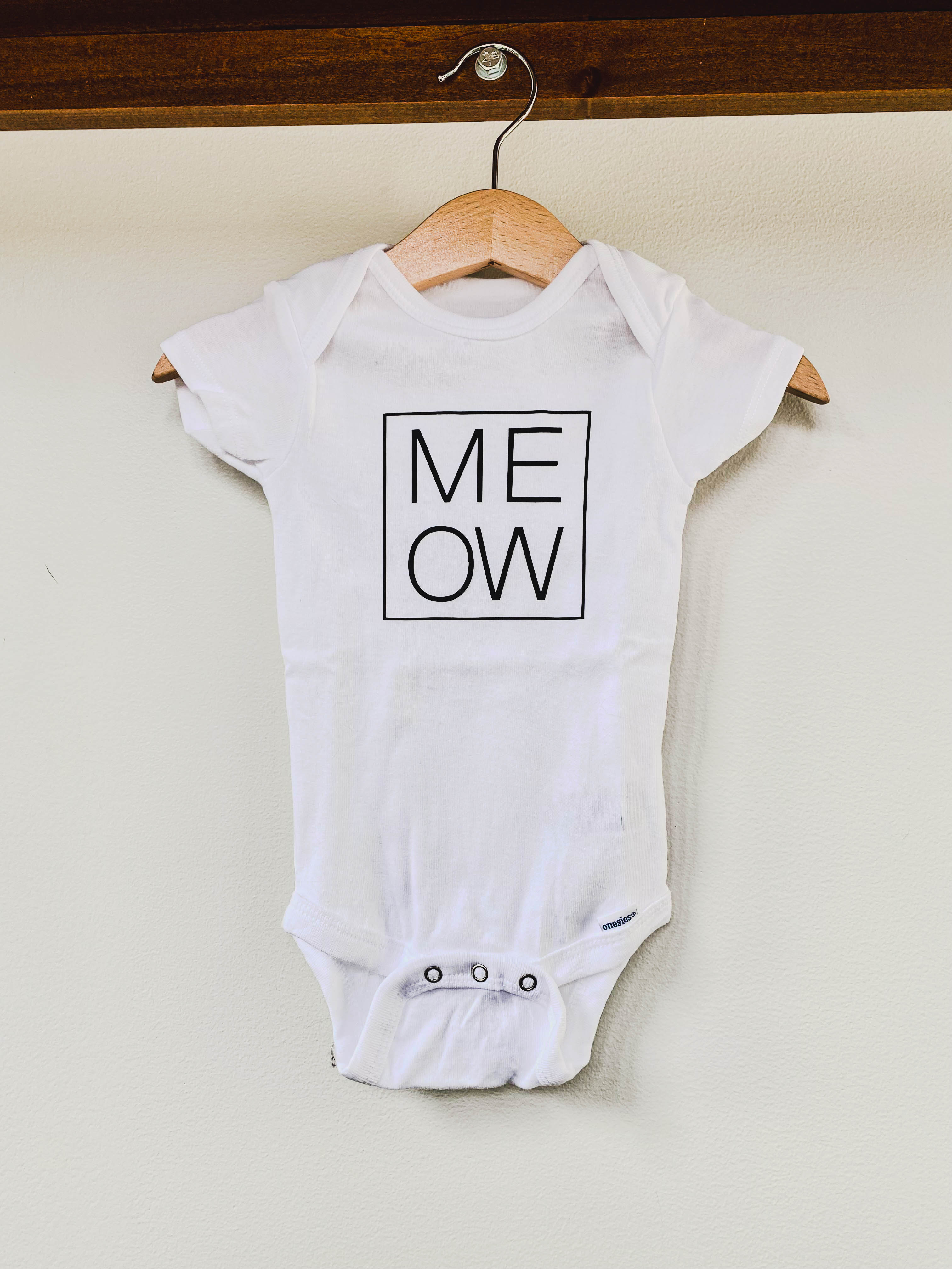 White baby onesie with 'MEOW' print
