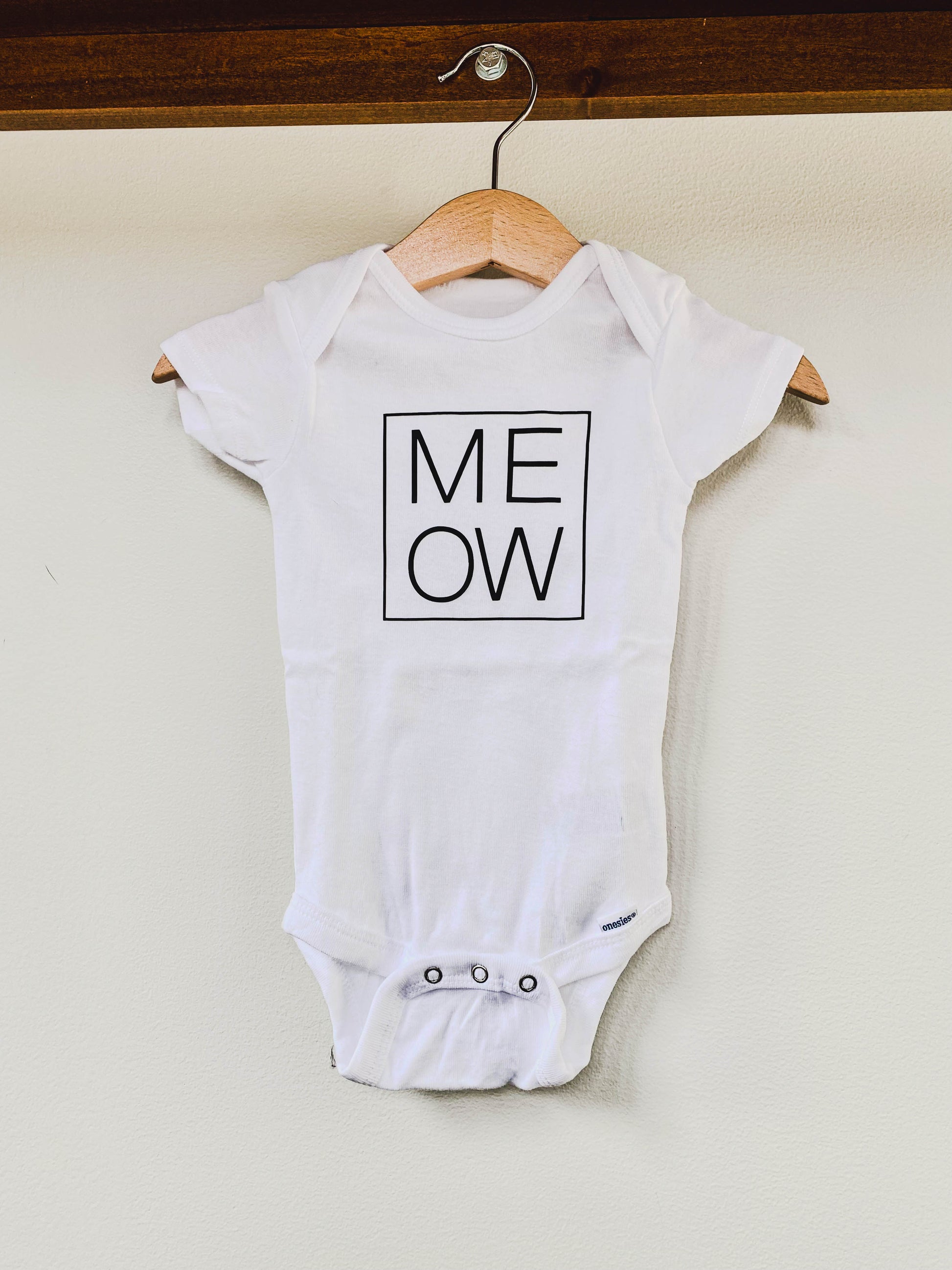 White baby onesie with 'MEOW' print