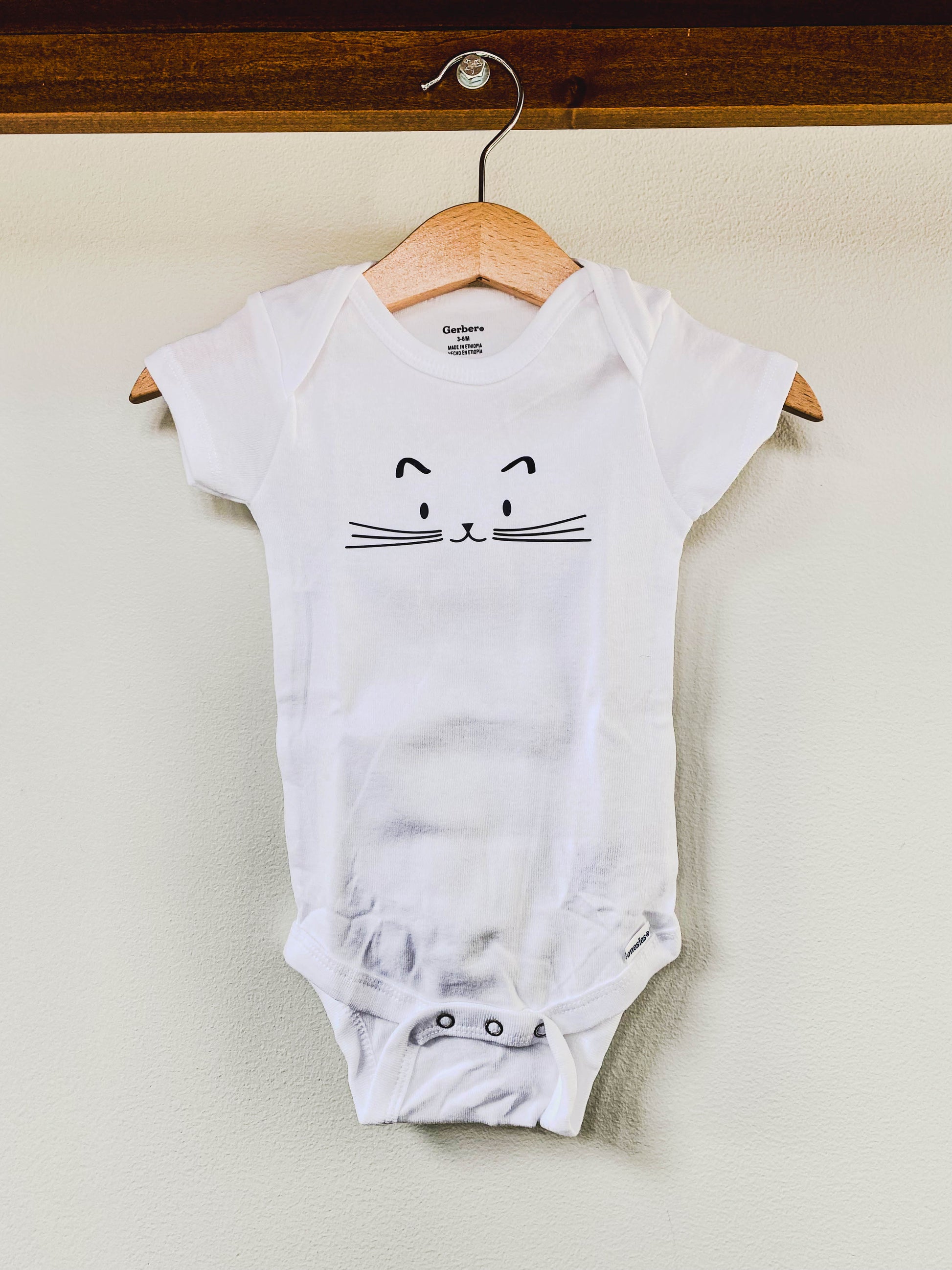 White baby onesie with a cat face design