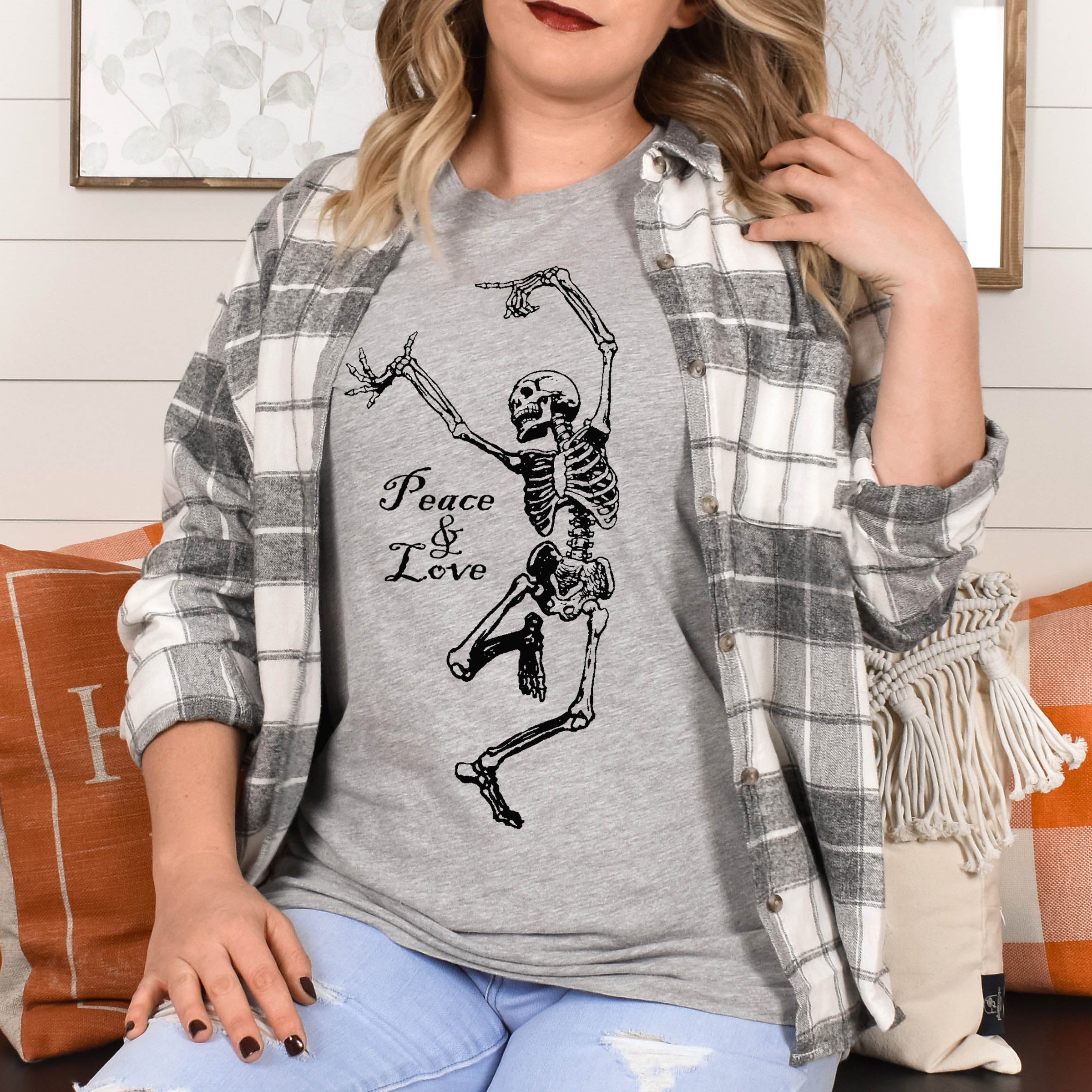Person wearing a gray t-shirt with a skeleton design and 'Peace & Love' text, sitting on a couch.