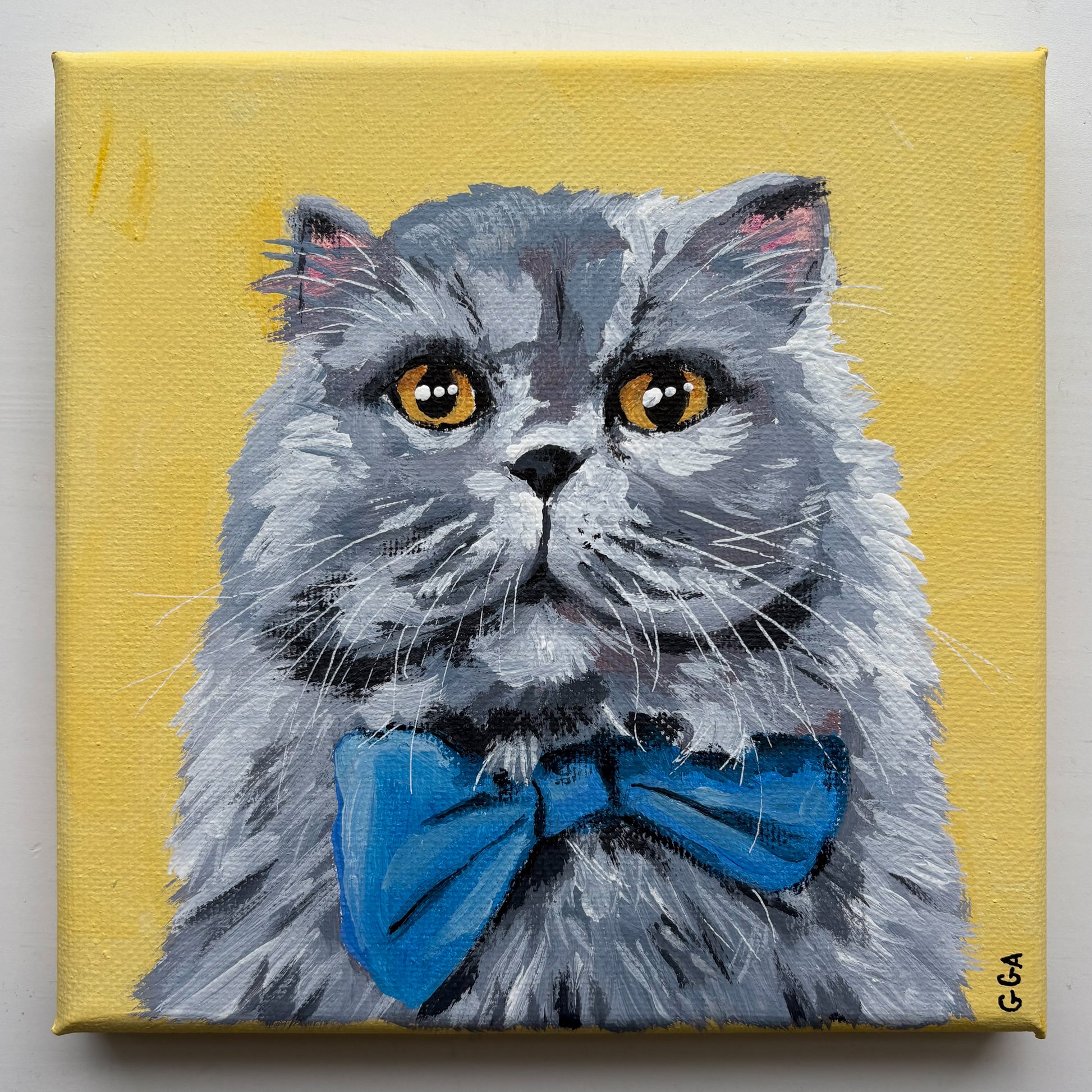 Painting of a cat with a blue bow tie on a yellow background