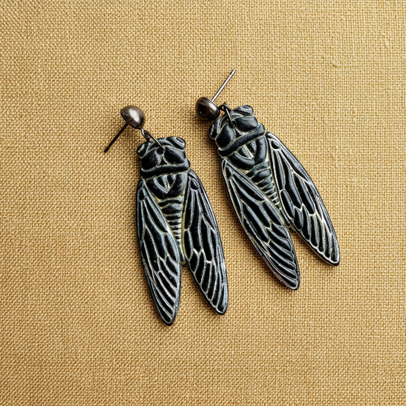 Cicada-shaped earrings on a white background