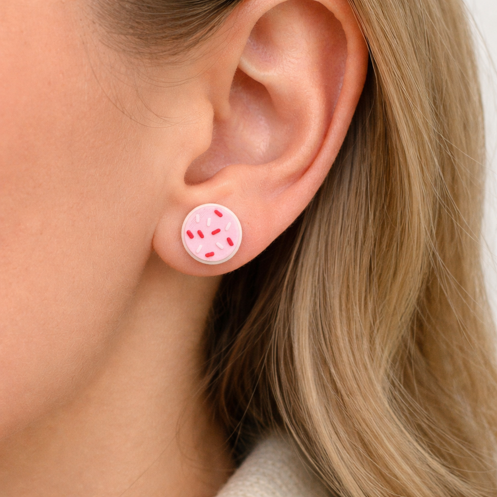 Close-up of an ear wearing a round pink earring with red accents.