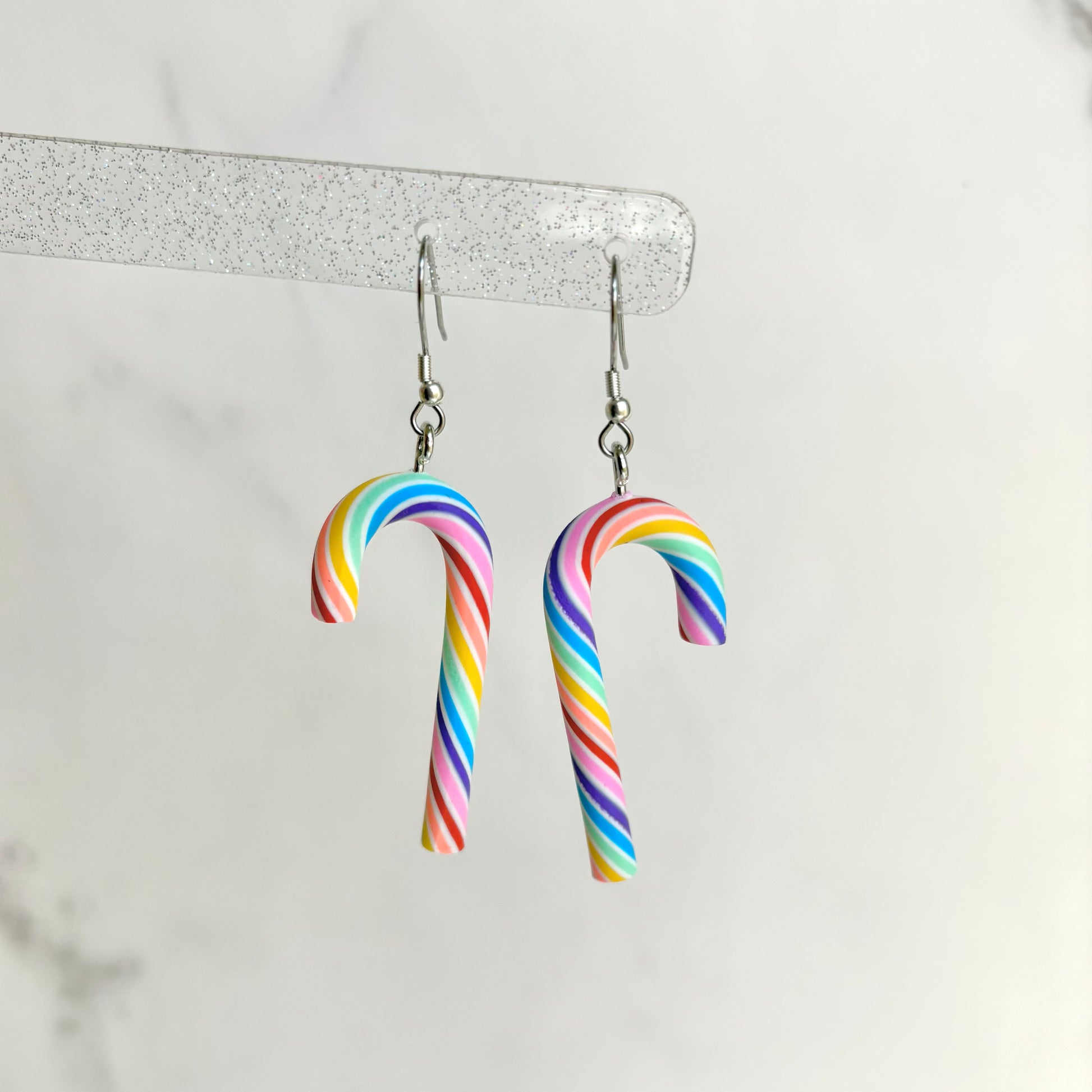 Rainbow striped candy cane earrings on a white background