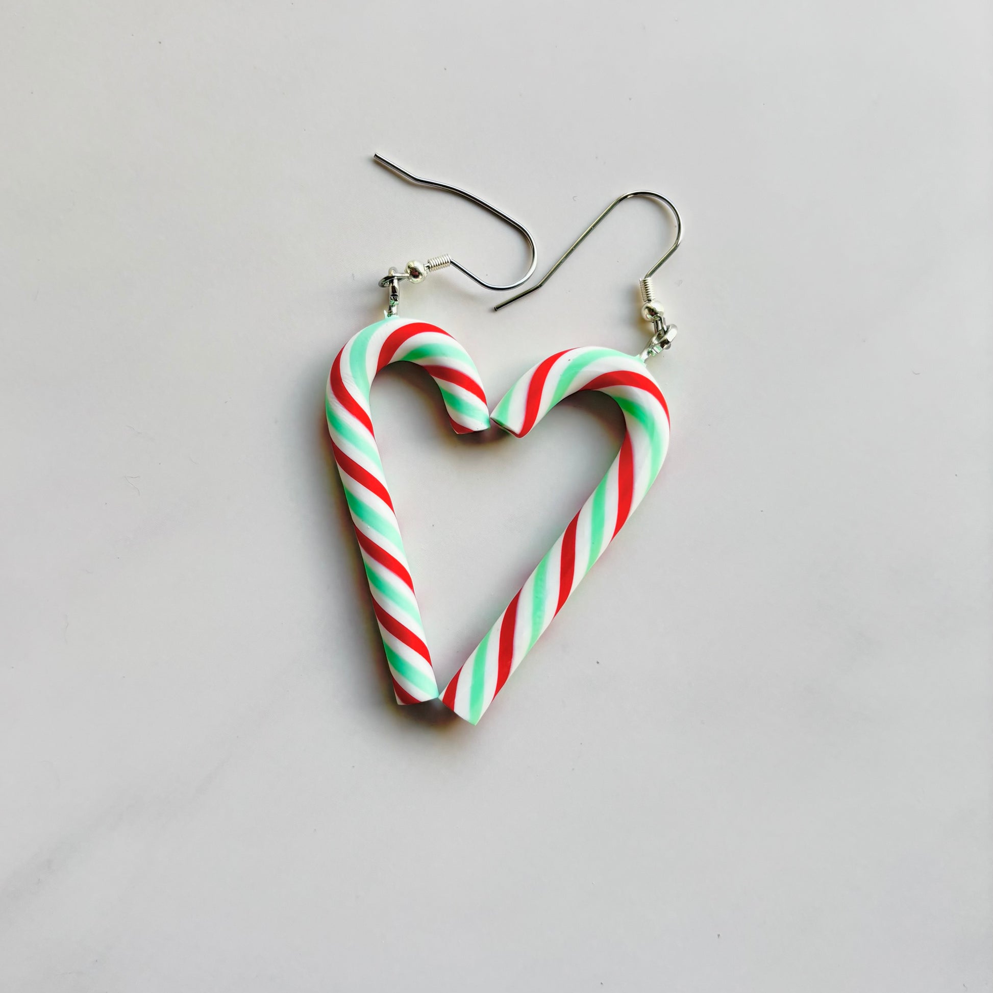 Heart-shaped candy cane earrings on a light gray background