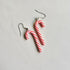 Candy cane-shaped earrings on a light gray background