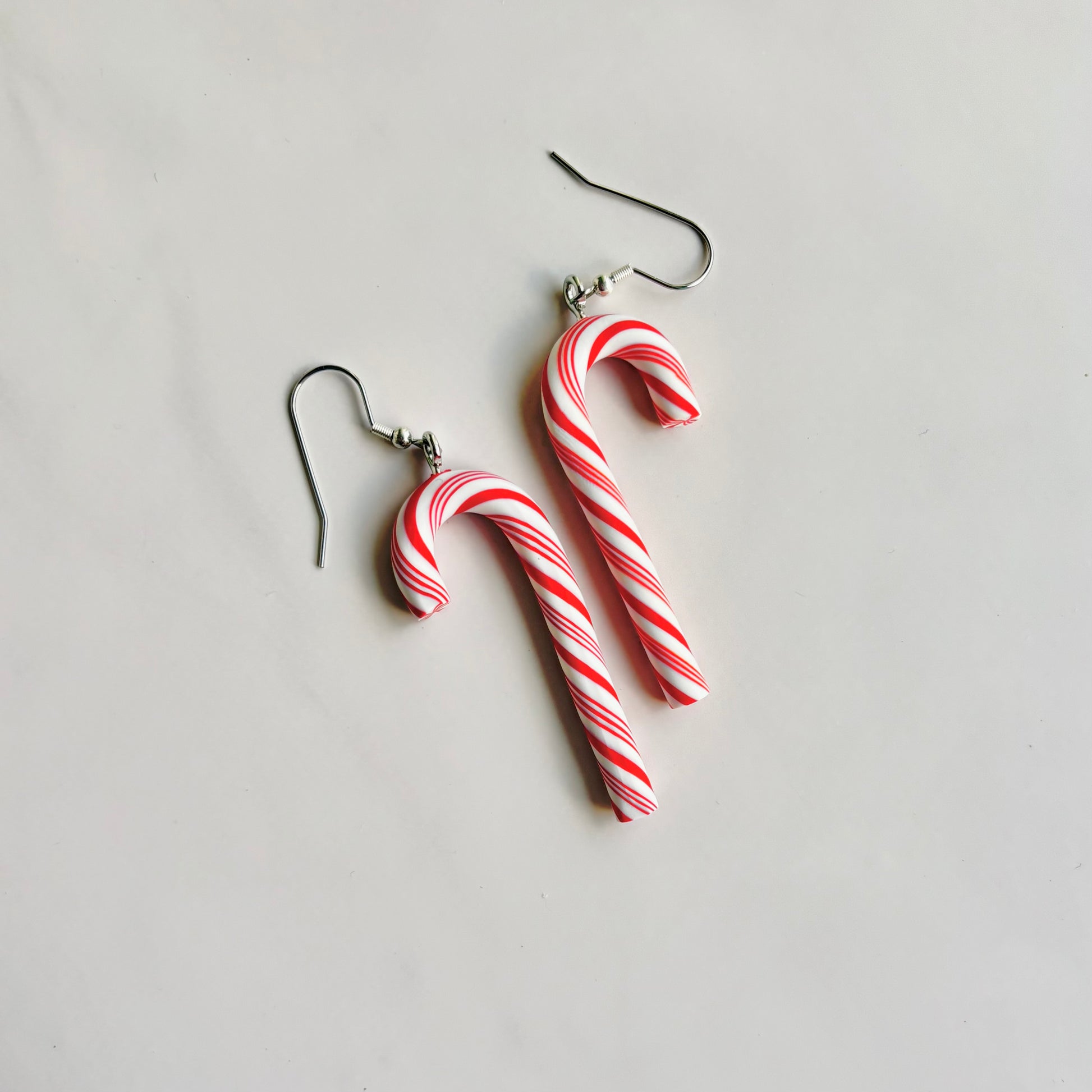Candy cane-shaped earrings on a light gray background