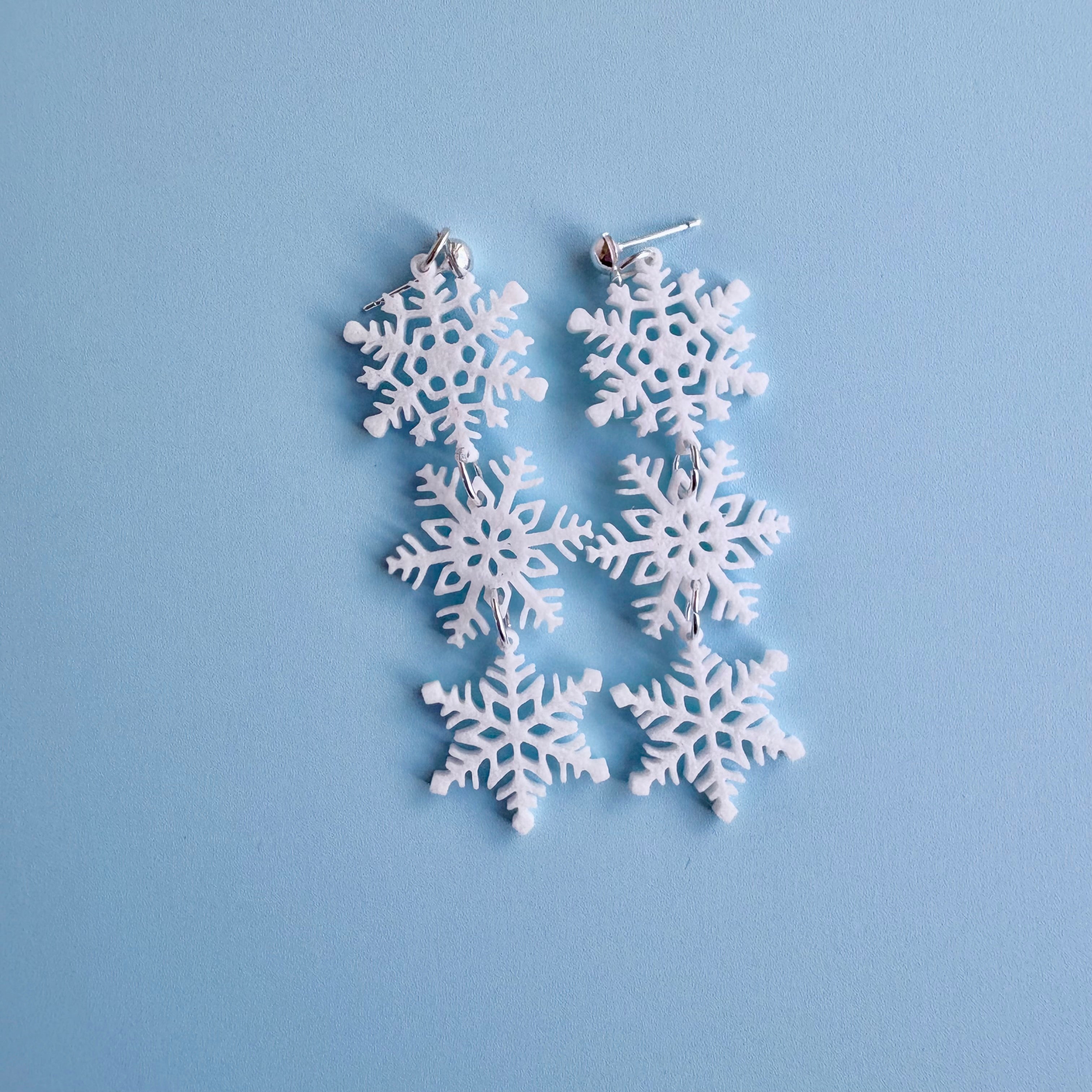 Snowflake-shaped earrings on a light blue background