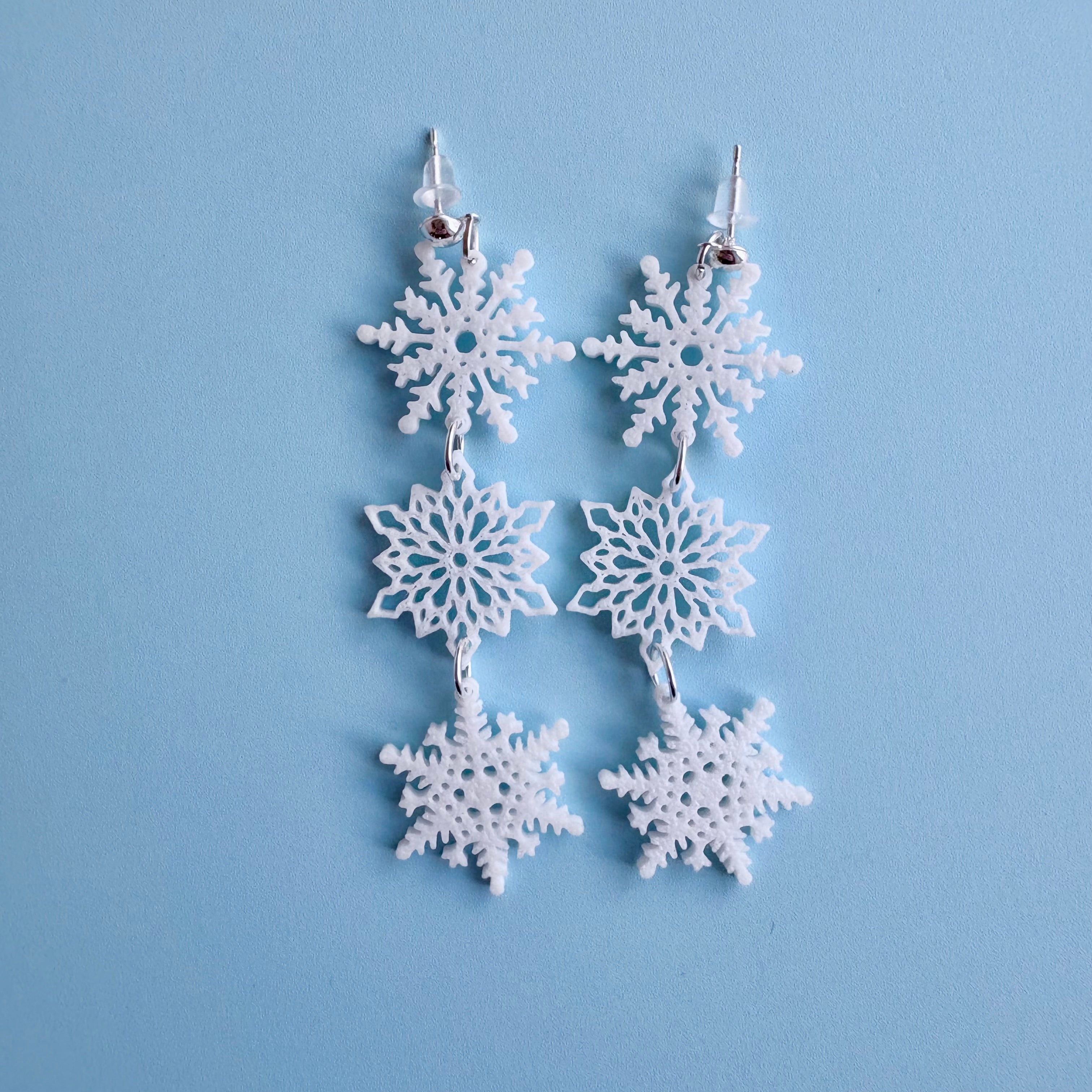 Snowflake earrings on a light blue background