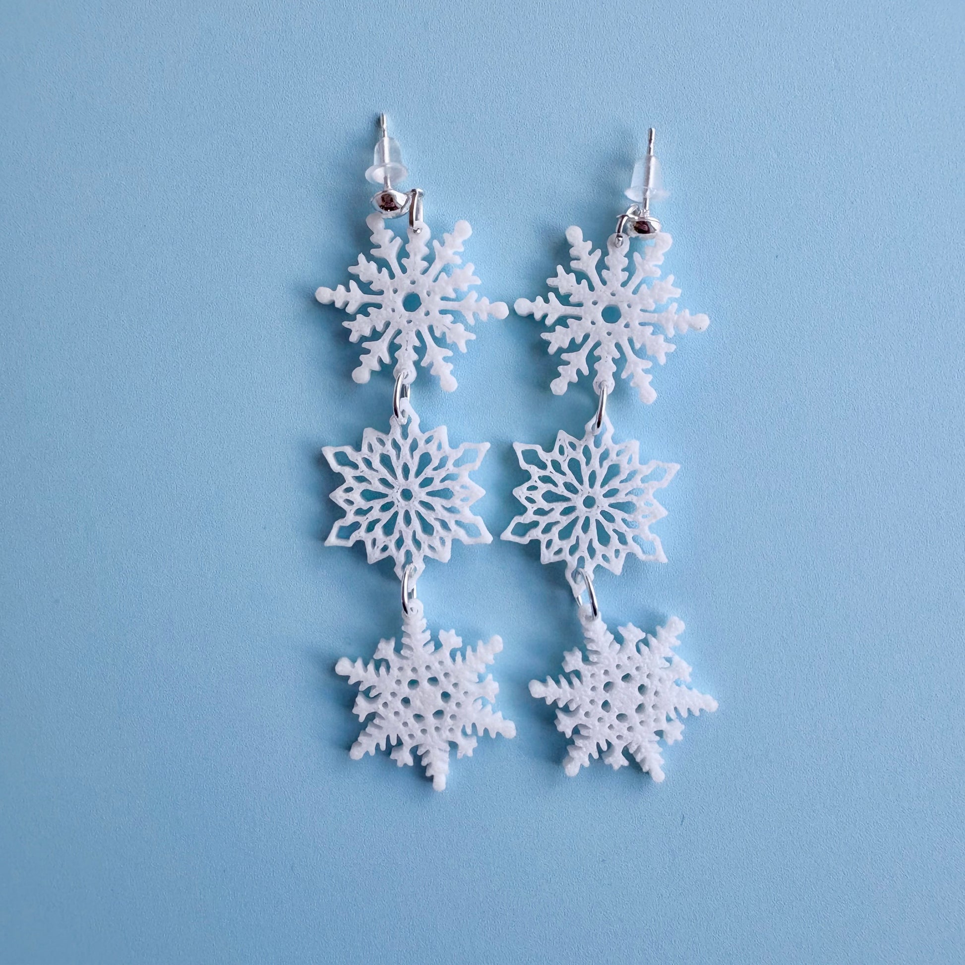 Snowflake earrings on a light blue background