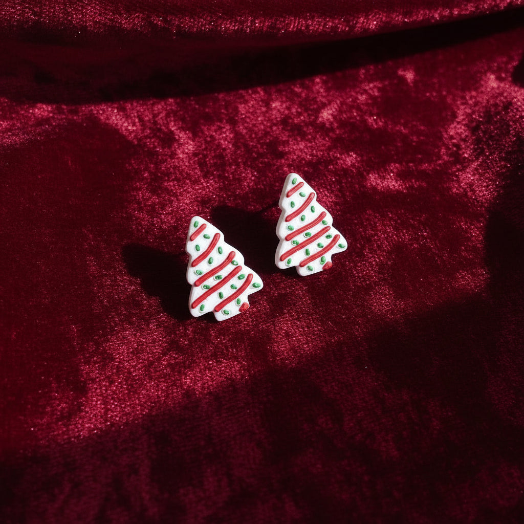 Christmas tree-shaped earrings with red and green details on a light gray background