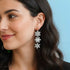 Woman wearing snowflake earrings against a light blue background