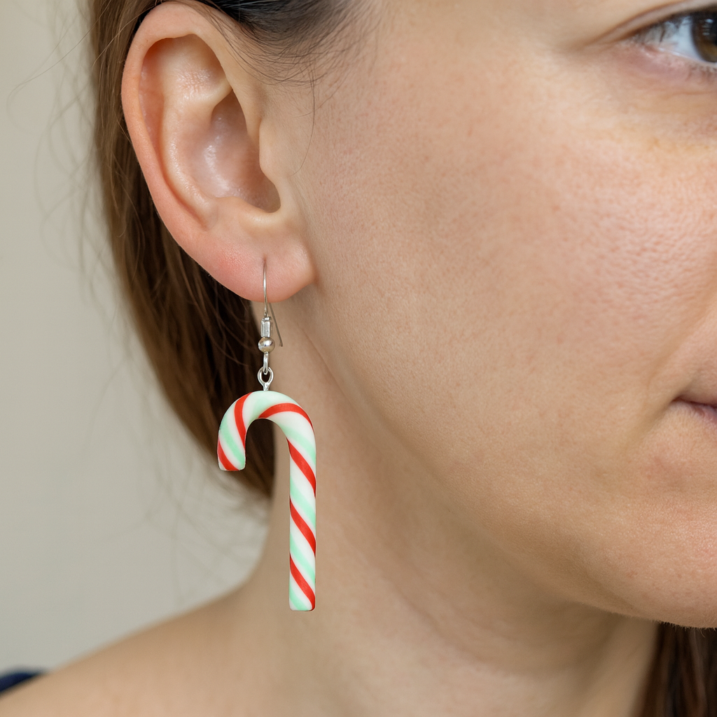 Close-up of a person wearing candy cane-shaped earrings.