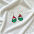 Grinch face earrings with Santa hats on a white background