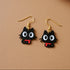 Black cat-shaped earrings with gold hooks on a white background