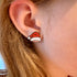 Close-up of an ear wearing a Santa hat earring with hair visible.