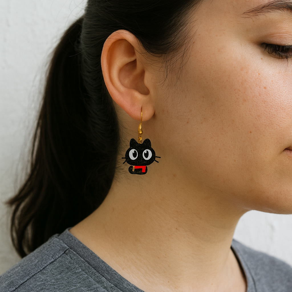 Person wearing a black cat-shaped earring with a red heart on a plain background