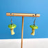 Mushroom-shaped earrings on a gold stand against a blue background