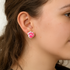 Close-up of a person wearing pink paw print earrings.