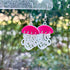 Jellyfish-shaped earrings with pink tops and white bottoms on a blurred natural background